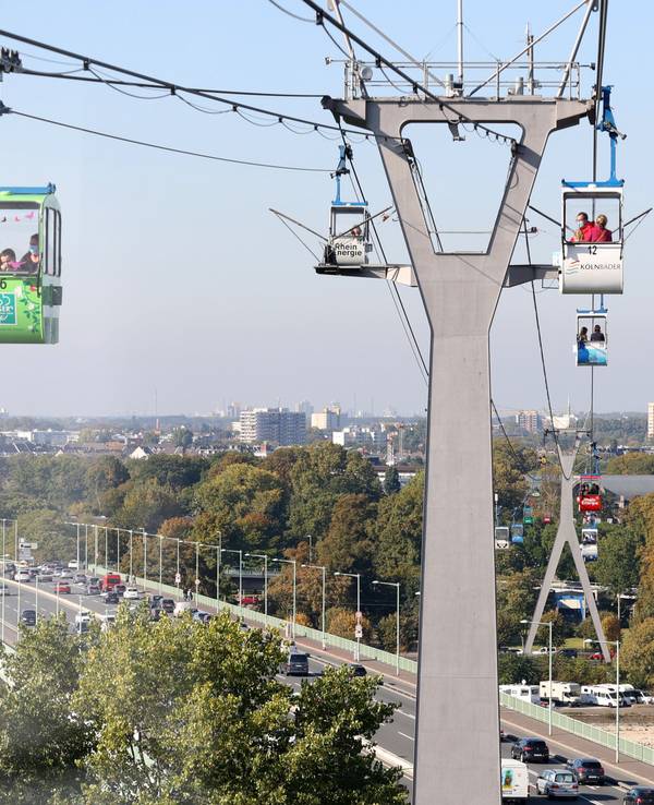 Gondeln der Kölner Seilbahn fahren über die Stadt.
