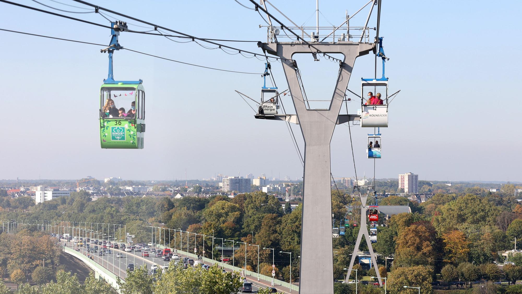 Gondeln der Kölner Seilbahn fahren über die Stadt.