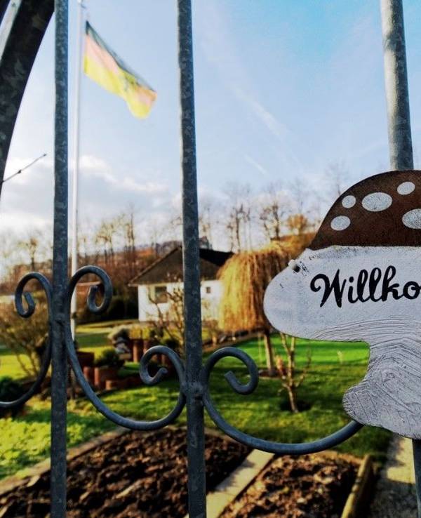 Ein Schild mit dem Schriftzug „Willkommen“ hängt am Tor eines Schrebergartens in einer Kleingartenanlage in Köln.