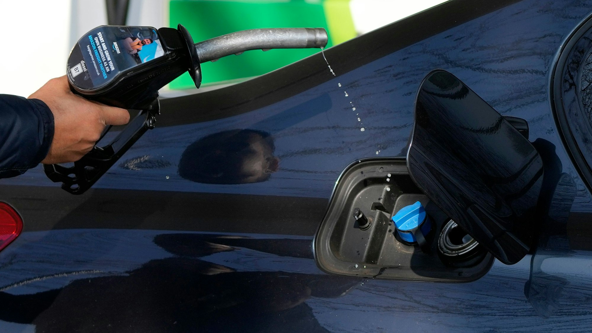 Ein Mann nimmt nach dem Tanken die Zapfpistole aus seinem Wagen. Die Preise für Benzin und Diesel haben durch den Krieg in der Ukraine neue Höchststände erreicht.
