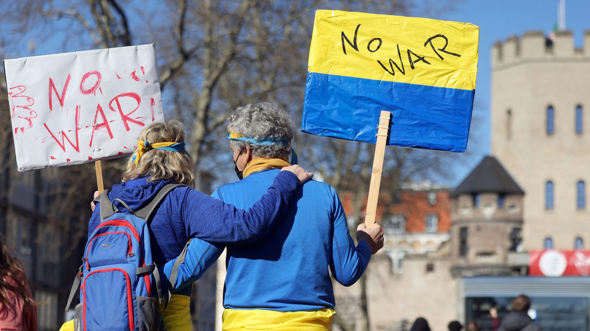 Mann und Frau zeigen Ukraine-Flagge auf einer Friedensdemo in Köln.