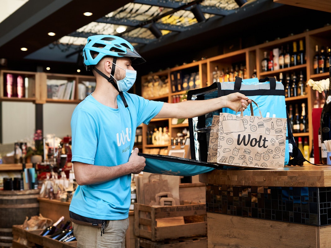 Ein Kurier des Lieferdienstes Wolt legt eine Tüte mit den Bestellungen auf einen Tisch.
