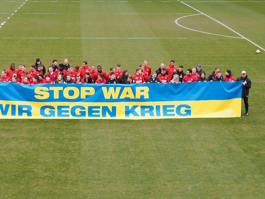 Spieler des 1. FC Köln und FK Krywbas posieren mit einem Anti-Kriegs-Banner.