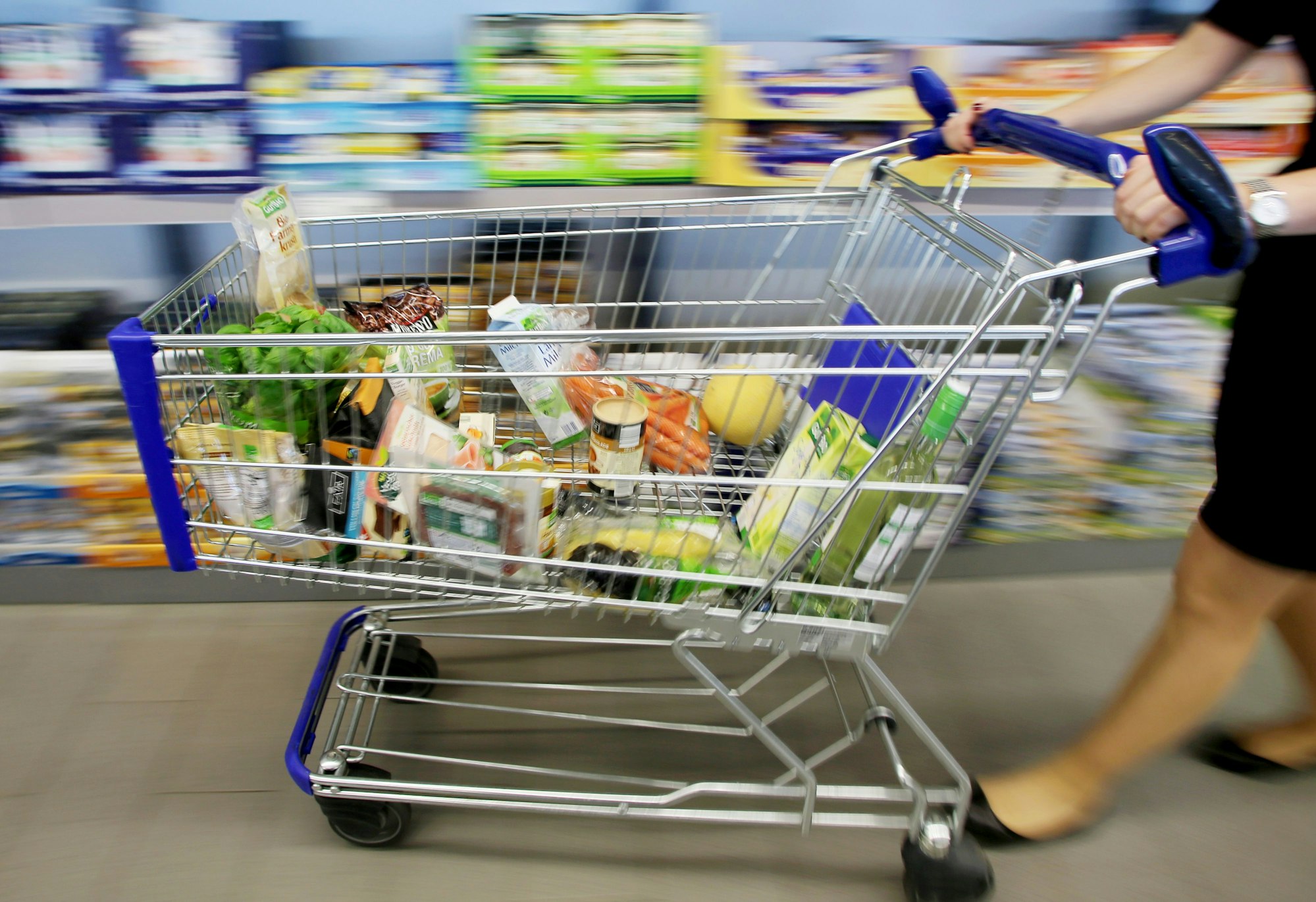 Eine Frau fährt einen Einkaufswagen durch eine Aldi-Filiale.