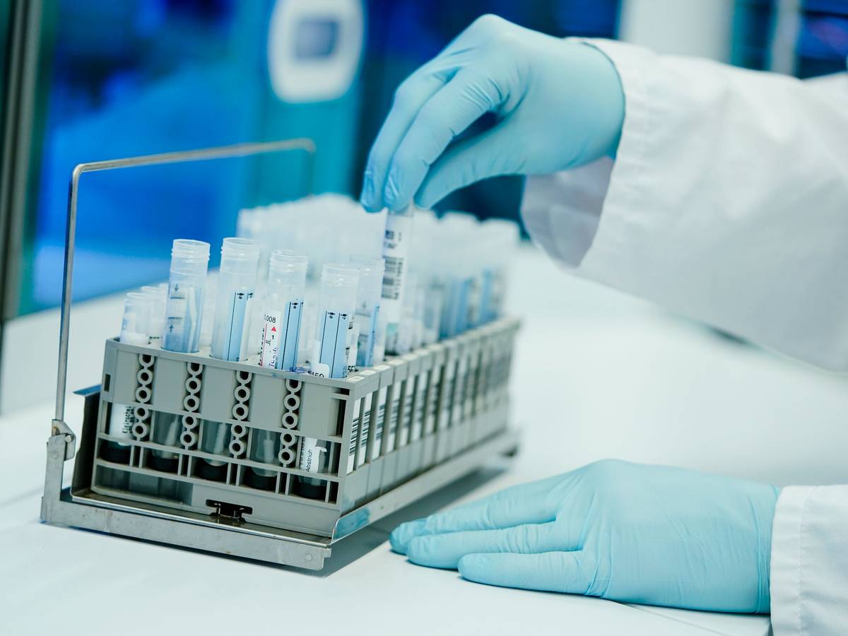 Ein Mitarbeiter hält in einem Coronatest-Labor PCR-Teströhrchen in den Händen.