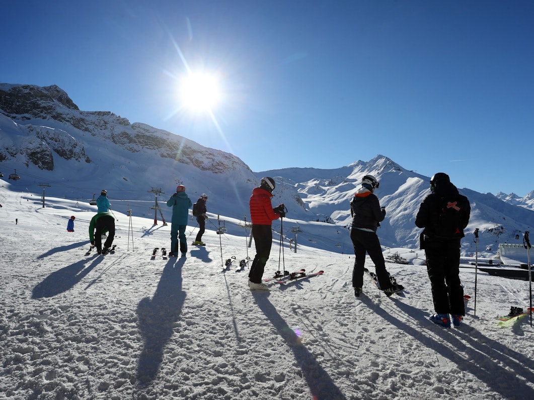 Wintersportler stehen im Skigebiet Ischgl im Sonnenschein.