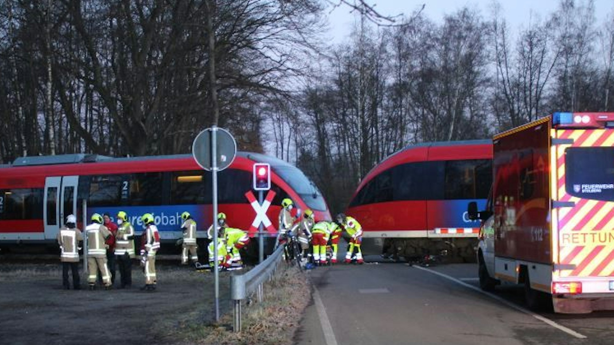 Einsatzkräfte von Feuerwehr und Rettungsdienst befinden sich an einem Bahnübergang, wo ein Unfall passiert ist.