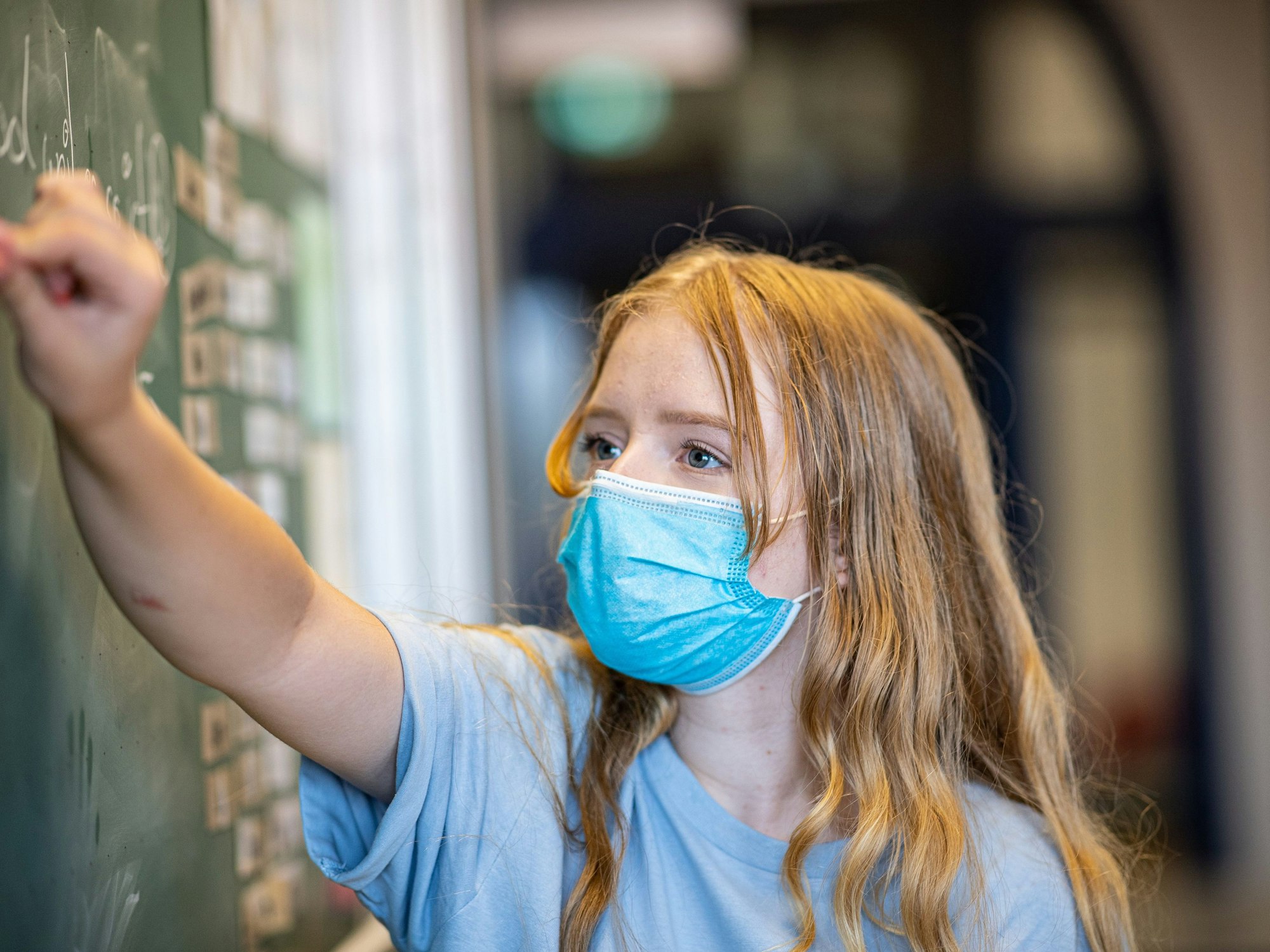 Eine Schülerin einer Gesamtschule steht mit einer Mund- und Nasenmaske vor einer Tafel. Zum 2. April 2022 fällt die Maskenpflicht an den Schulen in Nordrhein-Westfalen weg.