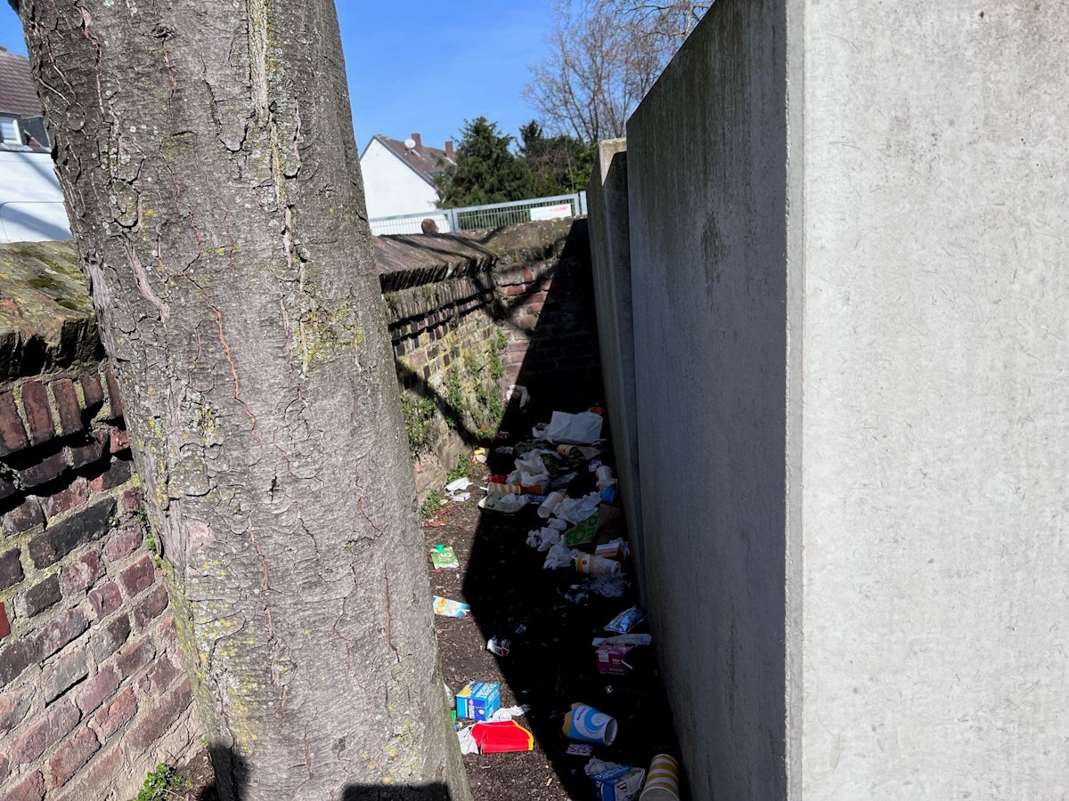 Müll hinter einer Mauer in der Hermesgasse in Köln-Niehl.