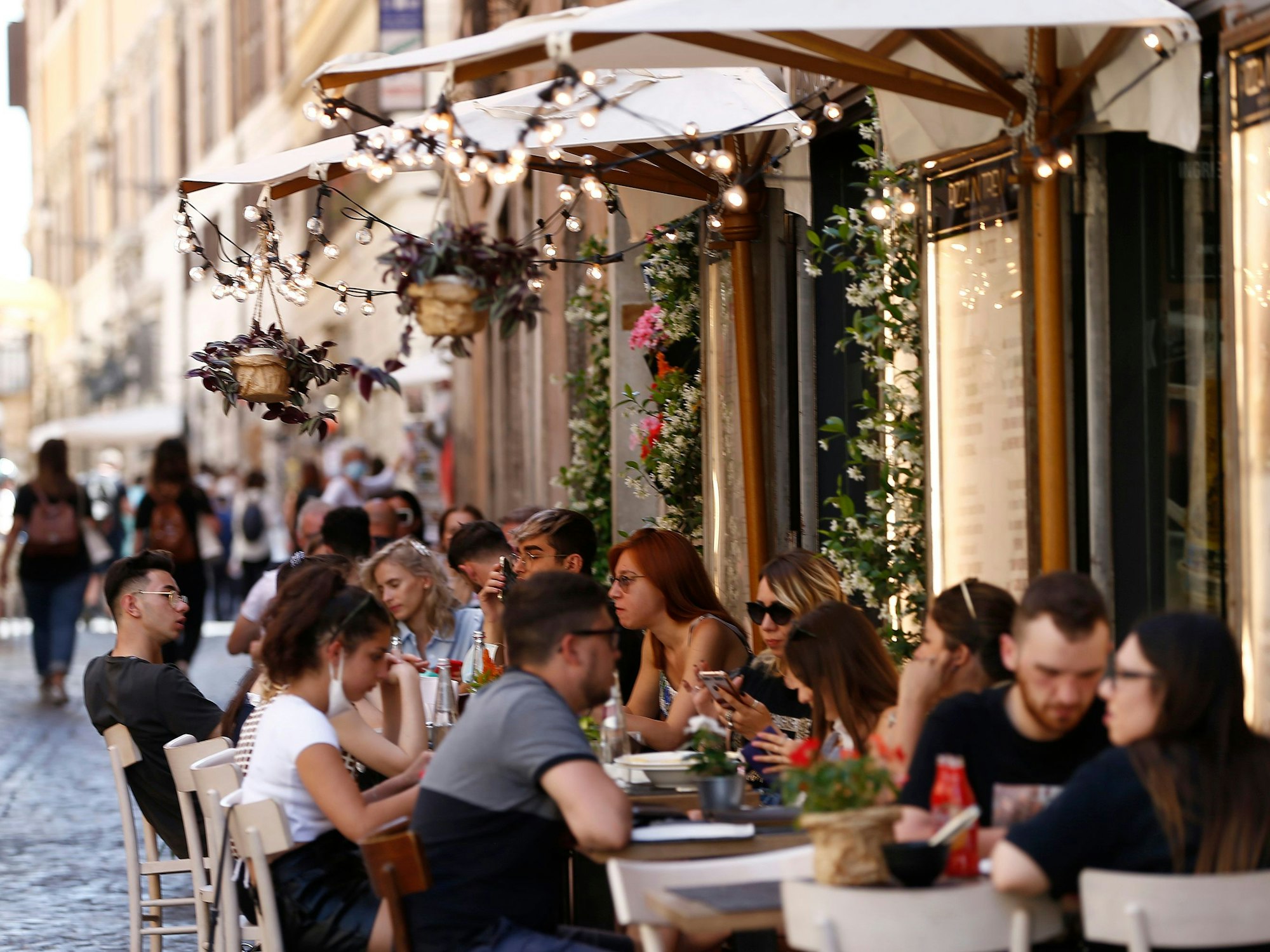Touristen sitzen im Außenbereich eines Restaurants in der Via delle Muratte. In Rom hält der Tourismus nach und nach wieder Einkehr.