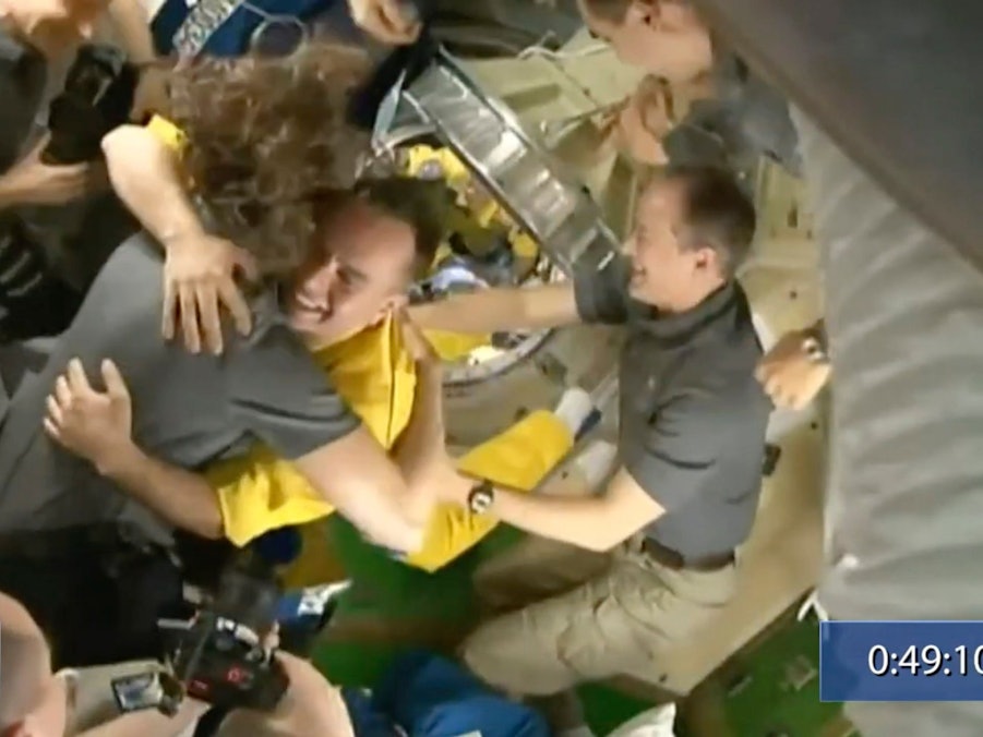 In diesem von Roskosmos zur Verfügung gestellten Video begrüßt die Besatzung der Internationalen Raumstation (ISS) drei russische Kosmonauten in gelber Kleidung, nachdem die Neuankömmlinge angedockt haben.