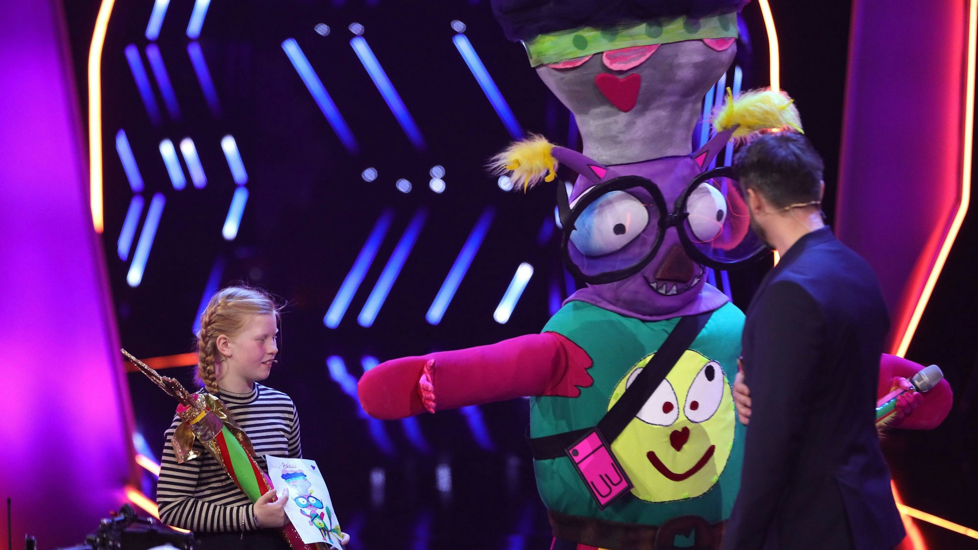 Brilli wurde von der zehnjährigen Emma (l.) für „The Masked Singer“ entworfen. Der Promi darunter musste zittern.
