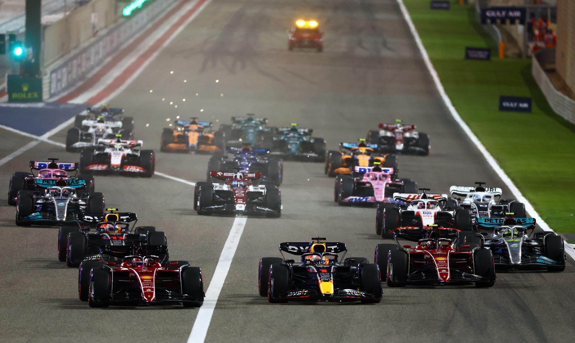 BAHRAIN, BAHRAIN - MARCH 20: Charles Leclerc of Monaco driving (16) the Ferrari F1-75 leads Max Verstappen of the Netherlands driving the (1) Oracle Red Bull Racing RB18 and the rest of the field going into the first corner at the start of the race during the F1 Grand Prix of Bahrain at Bahrain International Circuit on March 20, 2022 in Bahrain, Bahrain. (Photo by Mark Thompson/Getty Images)