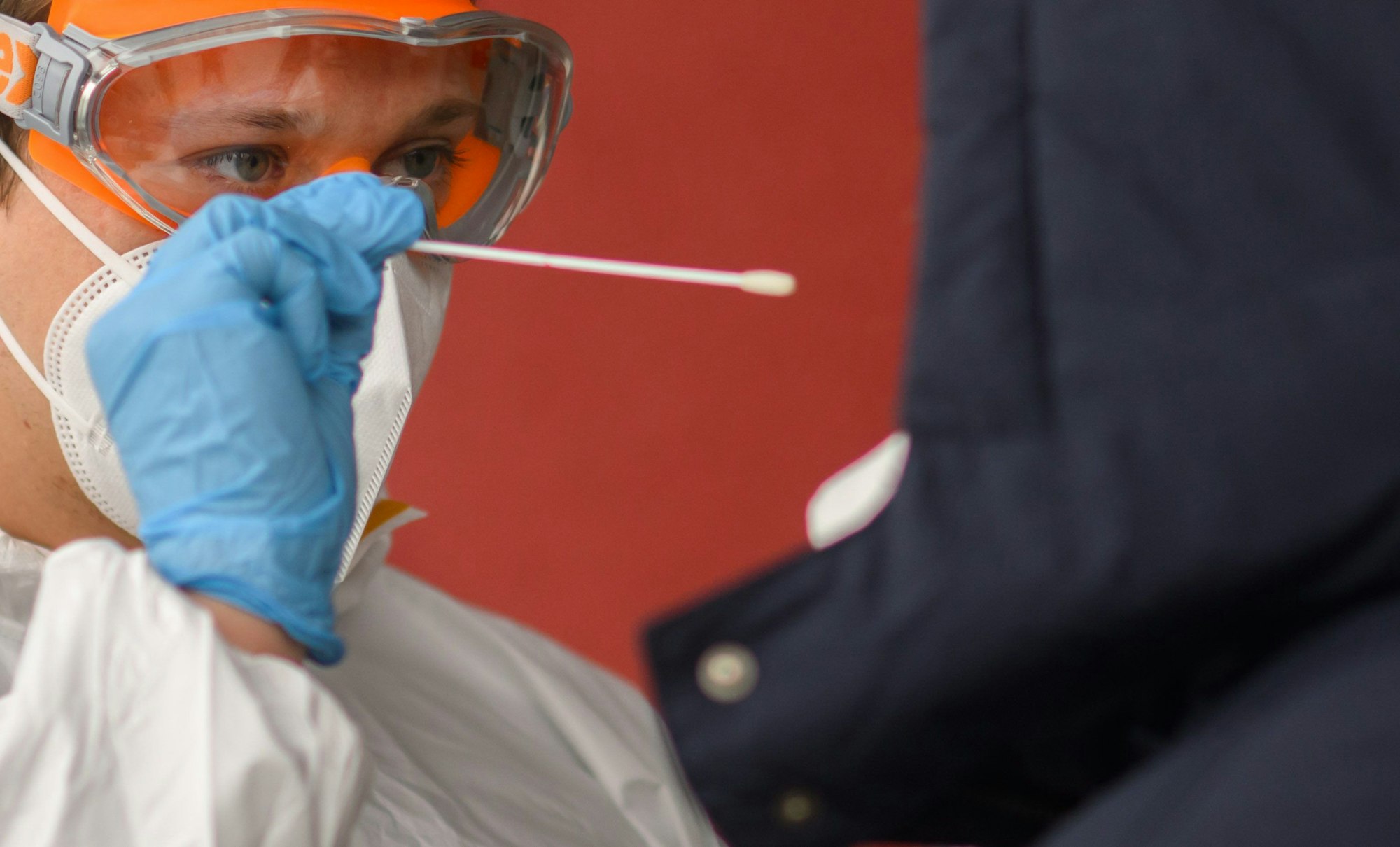 Ein Mitarbeiter nimmt einen Abstrich von einer Patientin für einen PCR-Test auf das Coronavirus vor einer Arztpraxis in der Region Hannover. Die bundesweite Sieben-Tage-Inzidenz stieg am Montag nach Angaben des Robert Koch-Instituts (RKI) wieder leicht an.