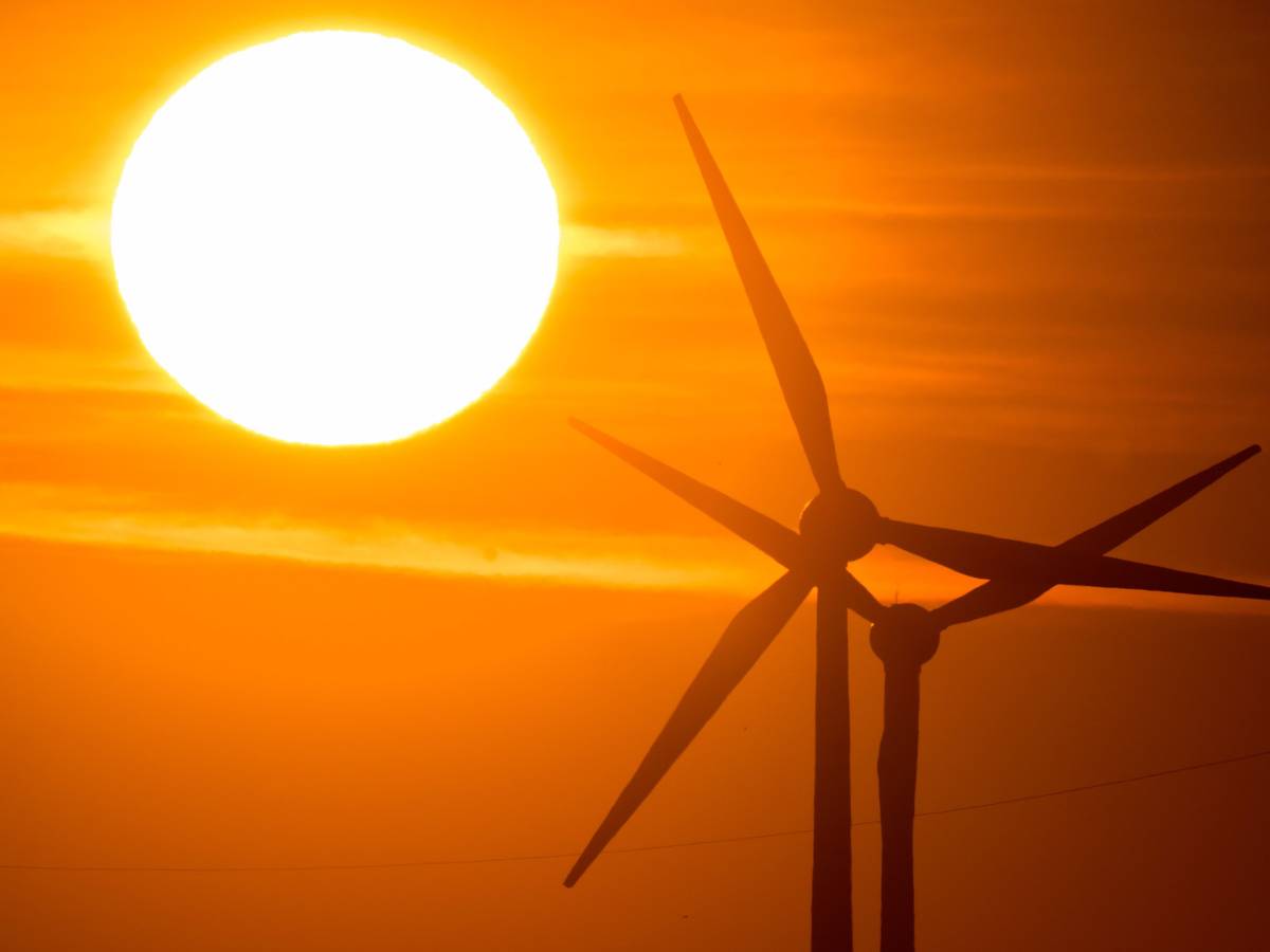 Die Sonne geht hinter Windrädern in der Region Hannover auf.