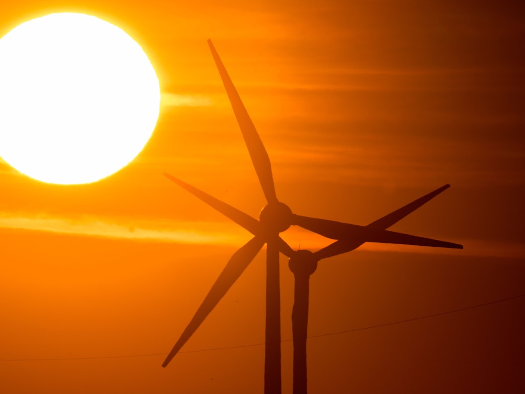 Die Sonne geht hinter Windrädern in der Region Hannover auf.