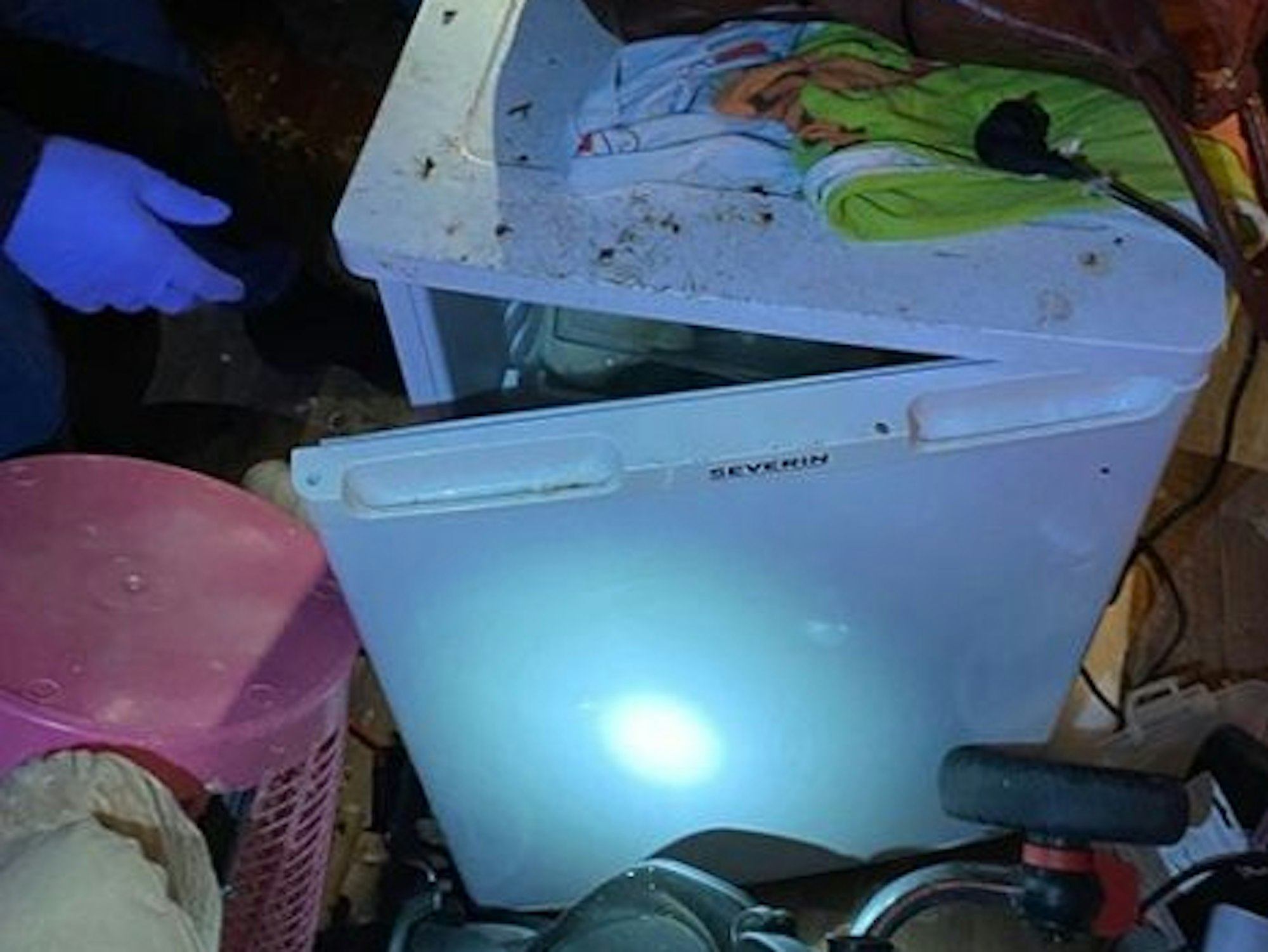 Ein dreckiger Kühlschrank steht inmitten von Gerümpel.