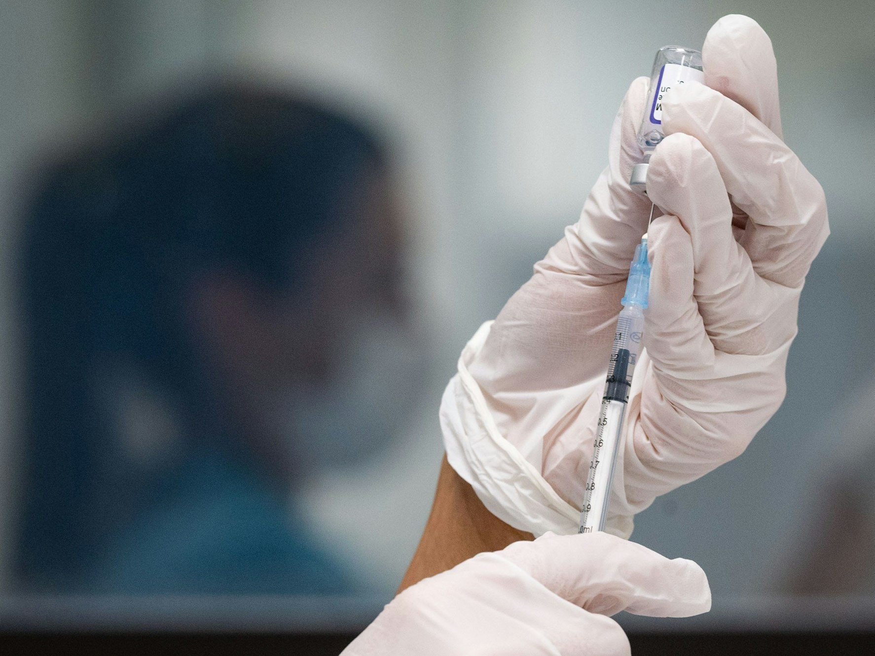 Eine Frau zieht eine Dosis des Impfstoffes von Biontech/Pfizer für eine Corona-Impfung auf.