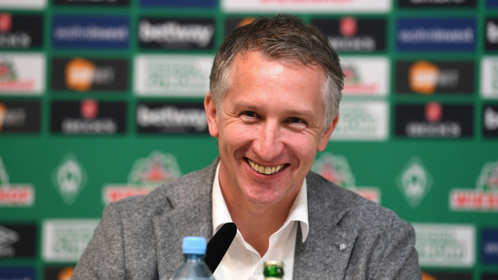 Frank Baumann lacht auf bei einer Pressekonferenz.