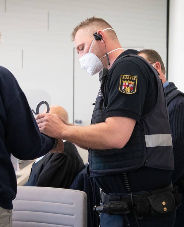 21.03.2022, Rheinland-Pfalz, Bad Kreuznach: Der Angeklagte wird in Handschellen in den Gerichtssaal gebracht. Der Mann soll im vergangenen Jahr in Bad Kreuznach den Mitarbeiter einer Tankstelle erschossen haben, nachdem dieser ihn auf die coronabedingte Maskenpflicht hingewiesen hatte.