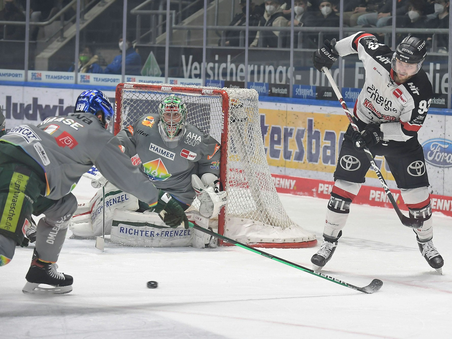 Sebastian Uvira (Kölner Haie, r.) spielt den Puck in Augsburg.