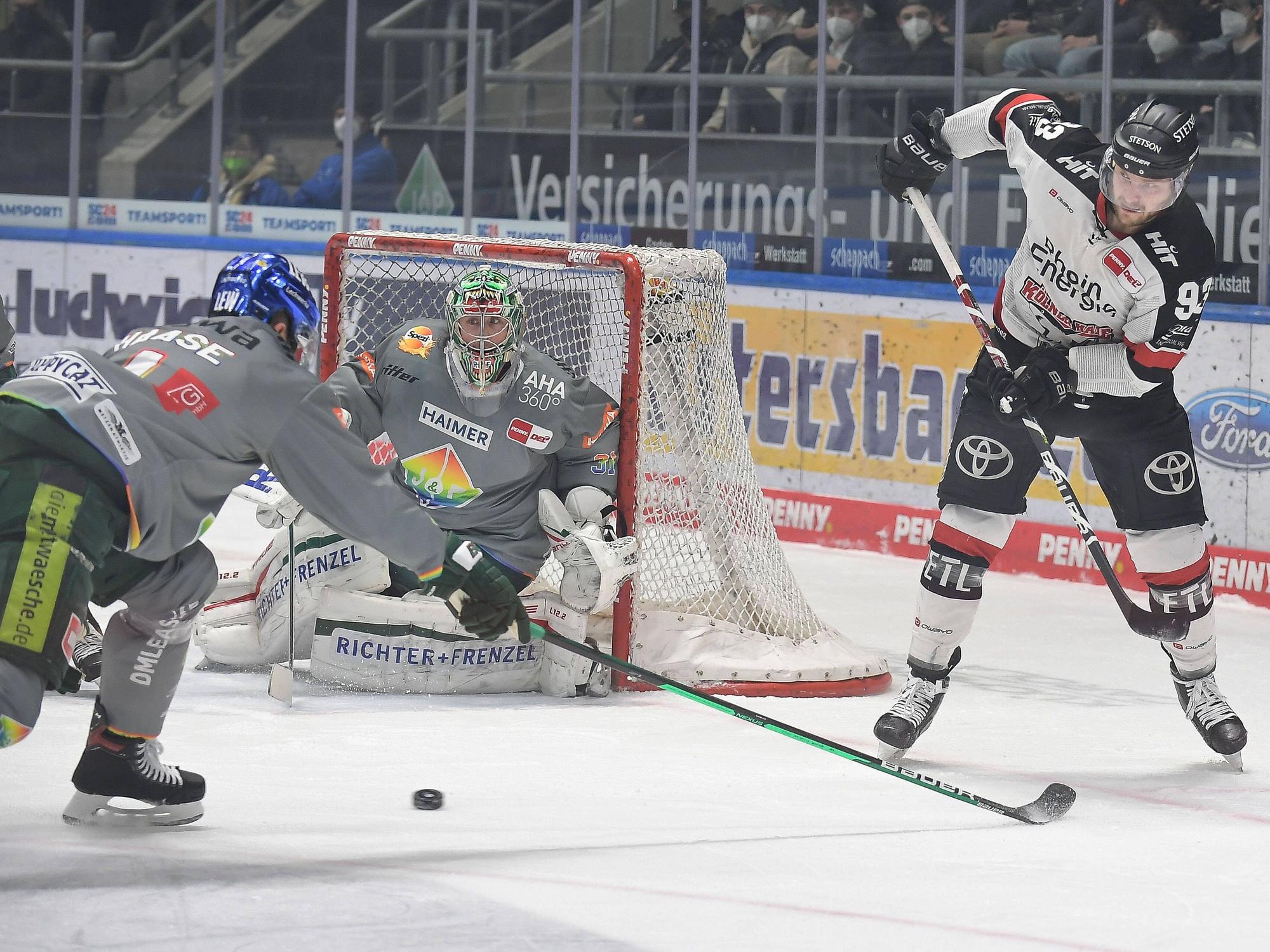 Sebastian Uvira (Kölner Haie, r.) spielt den Puck in Augsburg.