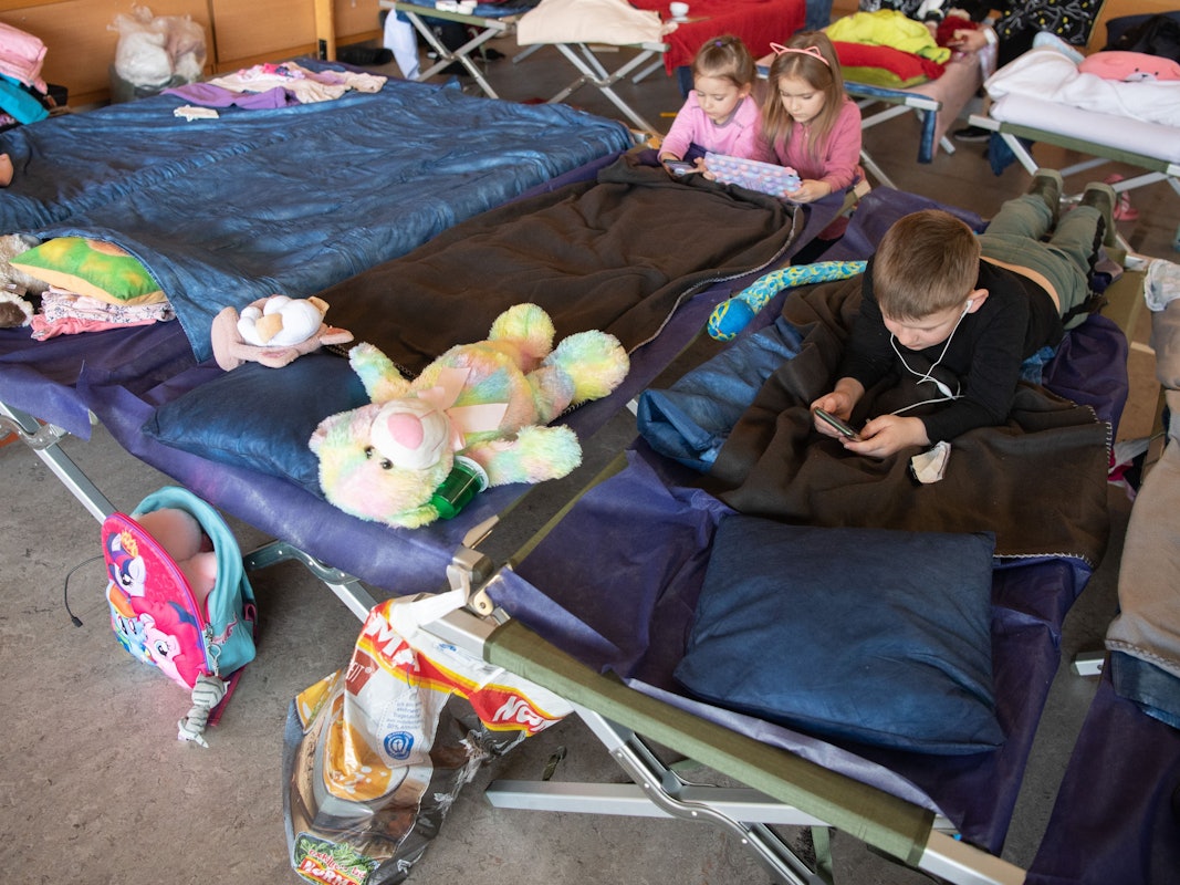 Geflüchtete Kinder aus der Ukraine liegen in der Notunterkunft auf ihren Feldbetten und vertreiben sich die Zeit.