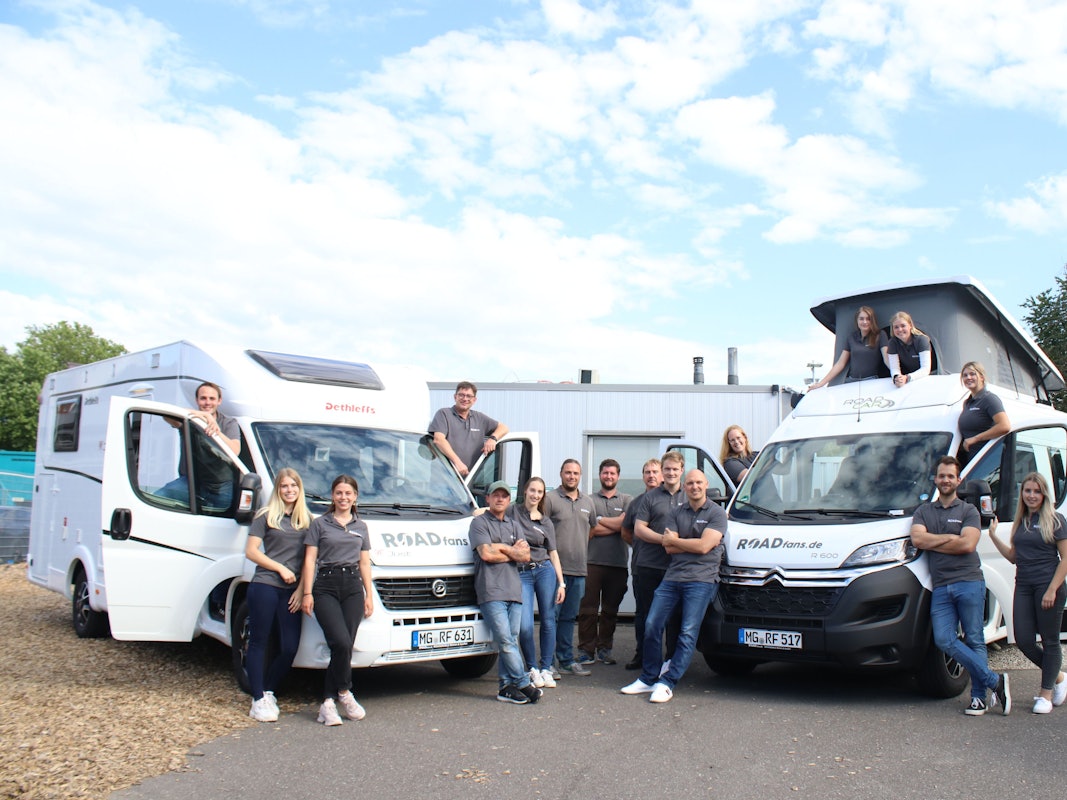 Das Team von roadfans steht vor zwei ihrer Fahrzeuge.