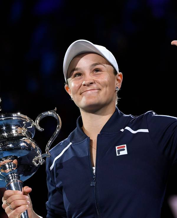 Ashleigh Barty hält den Pokal der Australian Open in der Hand und winkt.