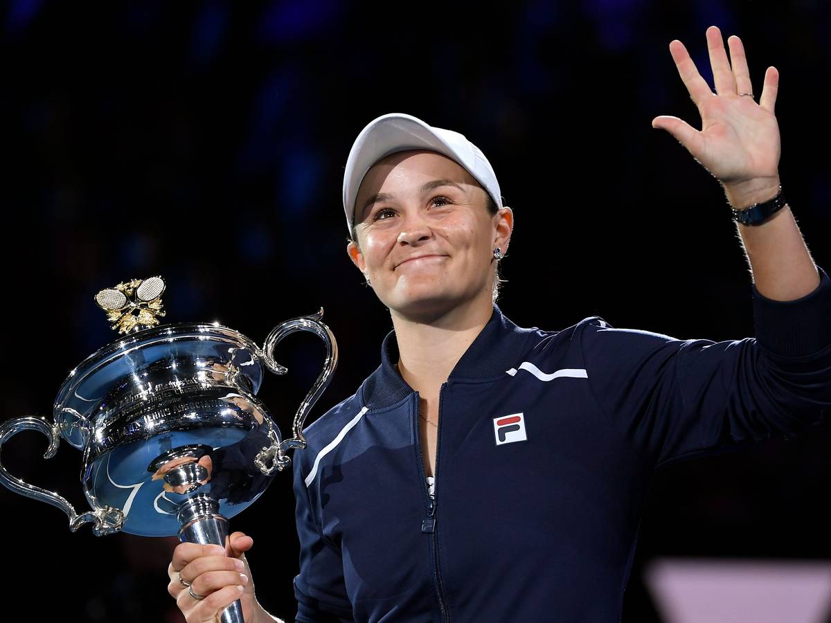 Ashleigh Barty hält den Pokal der Australian Open in der Hand und winkt.