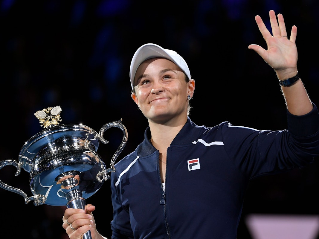 Ashleigh Barty hält den Pokal der Australian Open in der Hand und winkt.