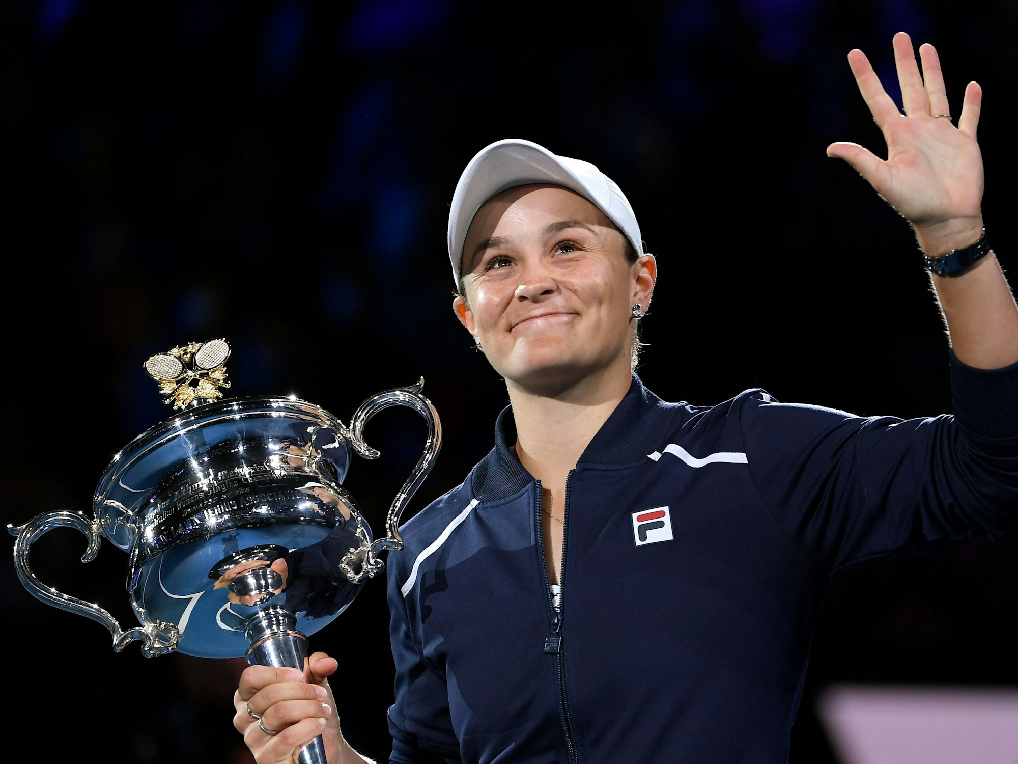 Ashleigh Barty hält den Pokal der Australian Open in der Hand und winkt.