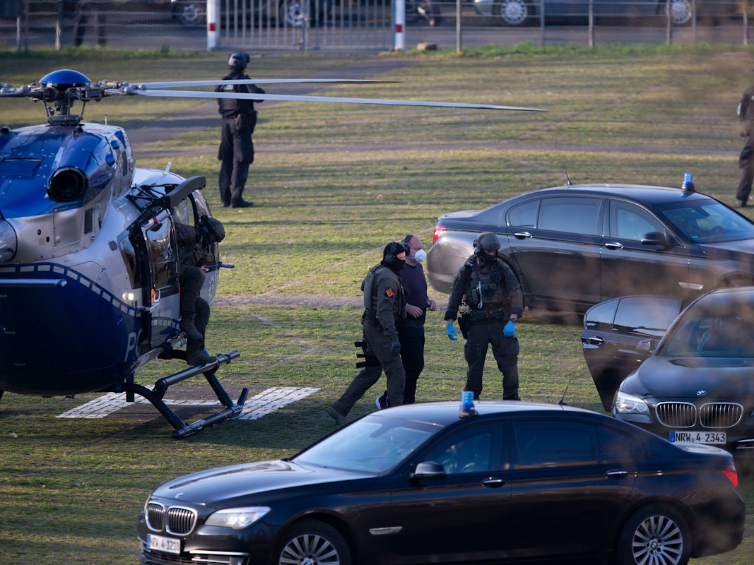 Der Angeklagte Thomas Drach kommt mit dem Hubschrauber auf dem Gelände des Justizzentrums Köln an und wird von zwei vermummten Polizisten begleitet.