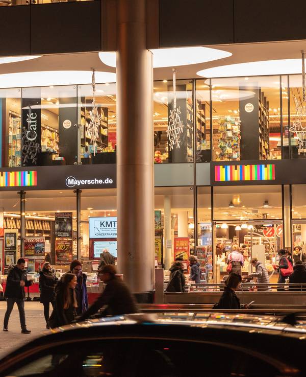 Die Mayersche Buchhandlung am Kölner Neumarkt hell erleuchtet in den Abendstunden.