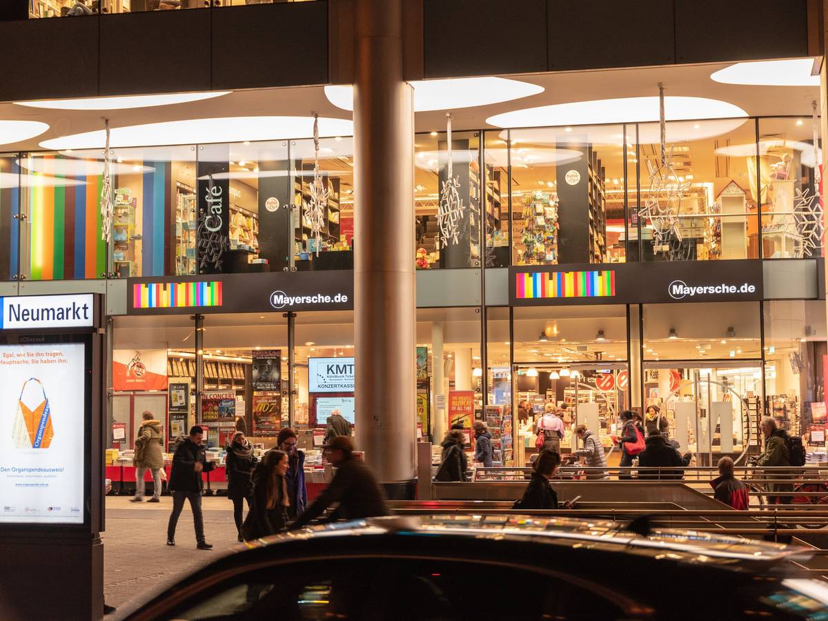Die Mayersche Buchhandlung am Kölner Neumarkt hell erleuchtet in den Abendstunden.