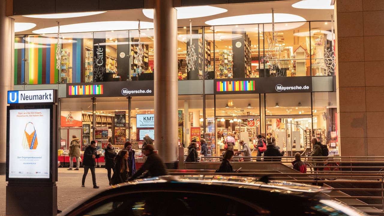 Die Mayersche Buchhandlung am Kölner Neumarkt hell erleuchtet in den Abendstunden.