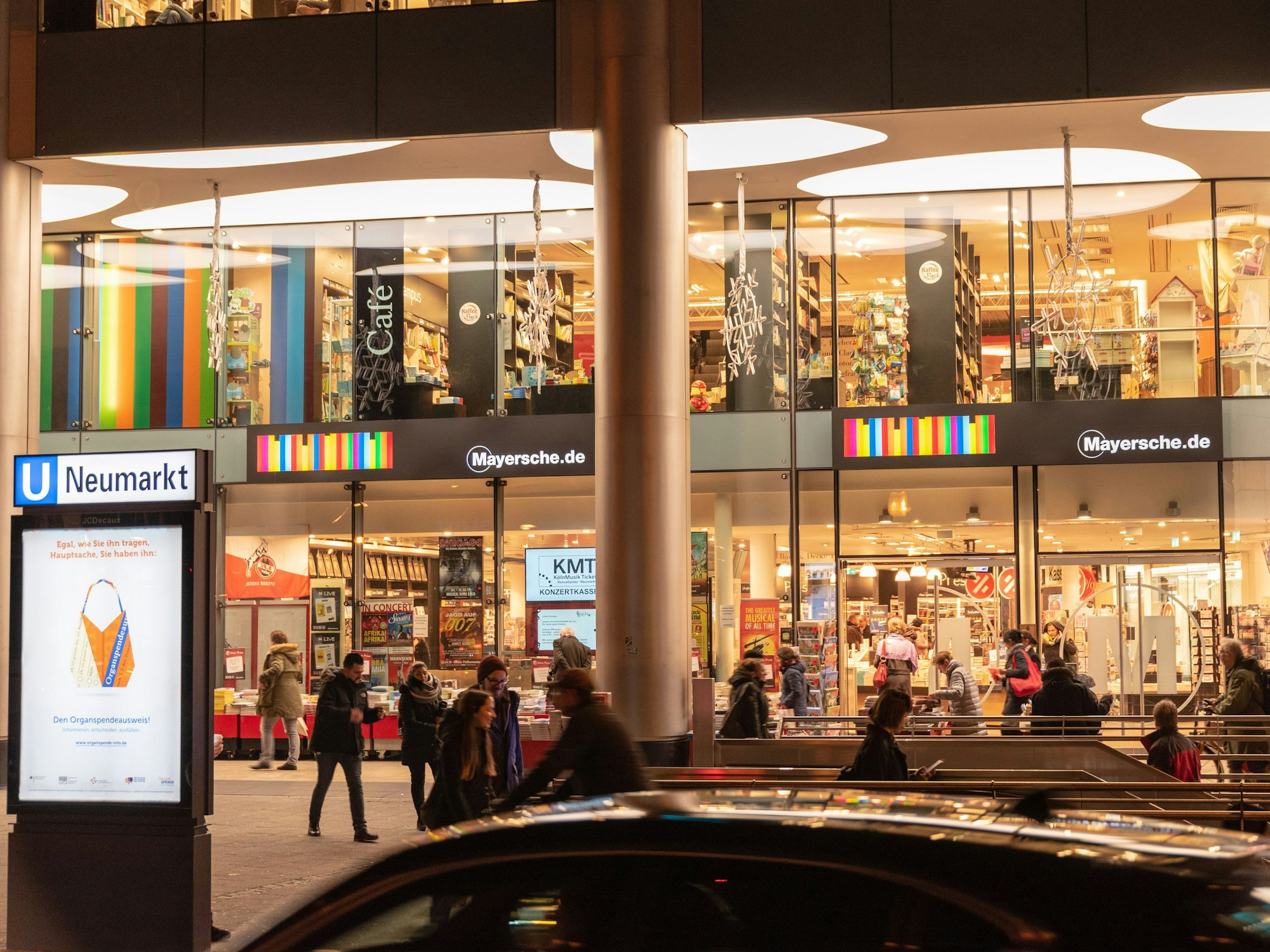 Die Mayersche Buchhandlung am Kölner Neumarkt hell erleuchtet in den Abendstunden.