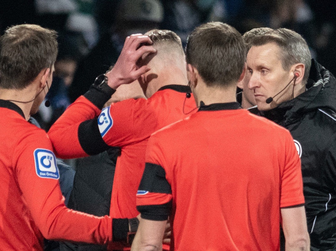Das Schiedsrichtergespann um Benjamin Cortuns verlässt während des Spiels das Spielfeld, nachdem der Linienrichter Christian Gittelmann (M) einen Gegenstand an den Kopf bekommen hatte.