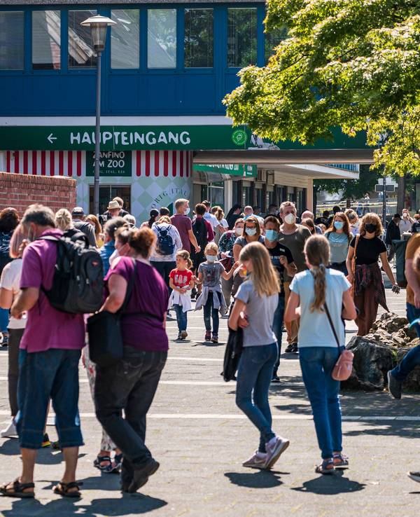 Menschen gehen bei Sonnenschein am Kölner Zoo vorbei.