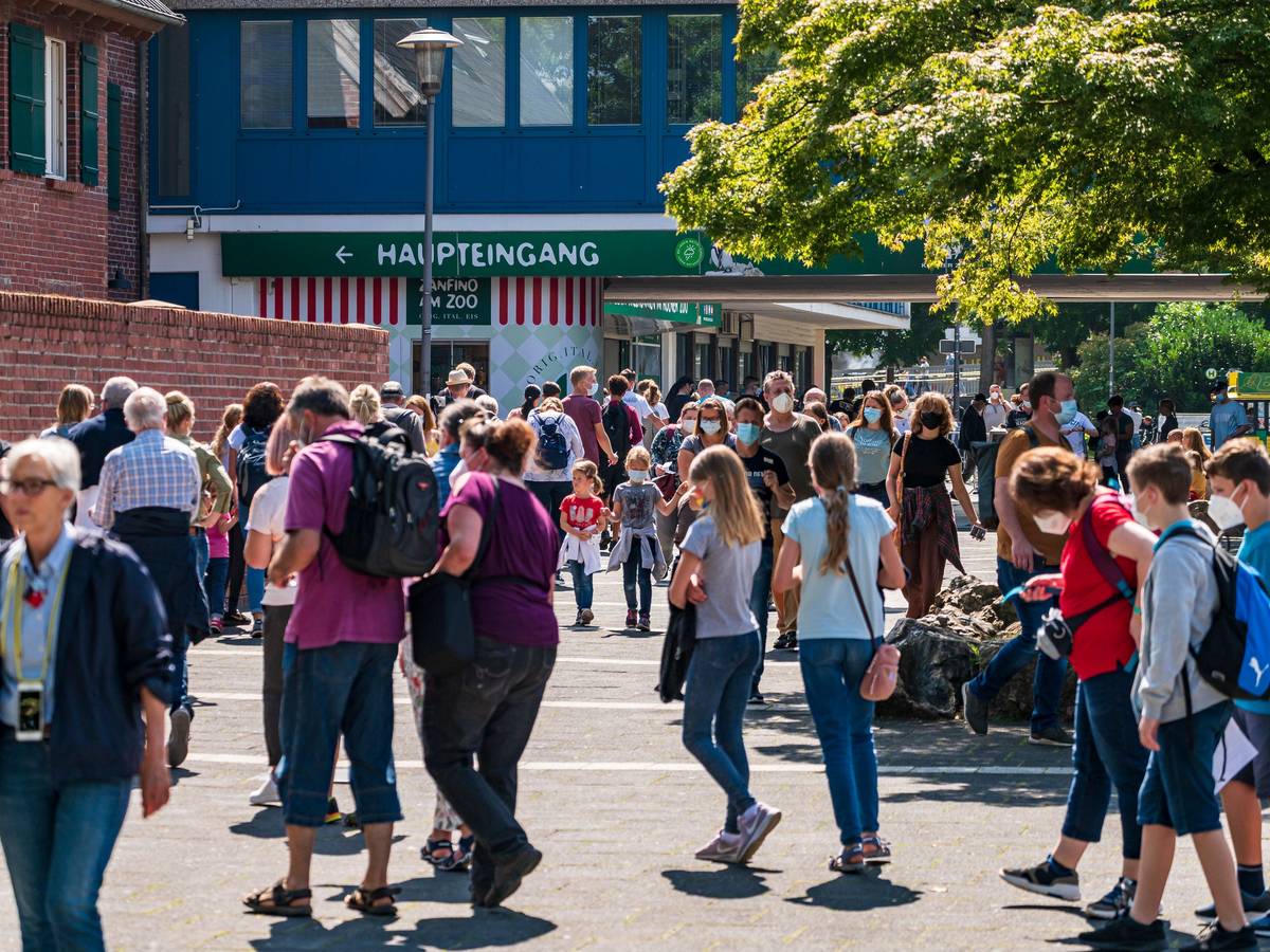 Menschen gehen bei Sonnenschein am Kölner Zoo vorbei.
