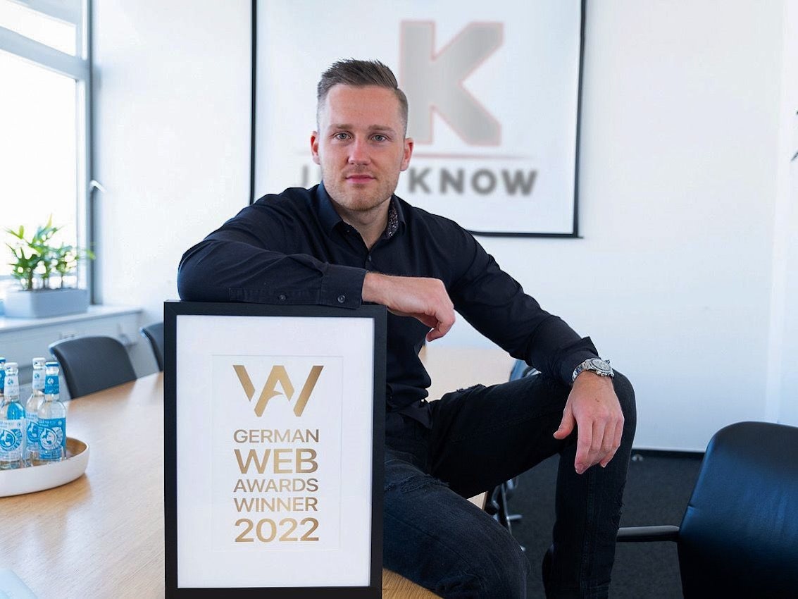 Gründer Jens Kröger sitzt in seinem Büro mit dem German Web Award.