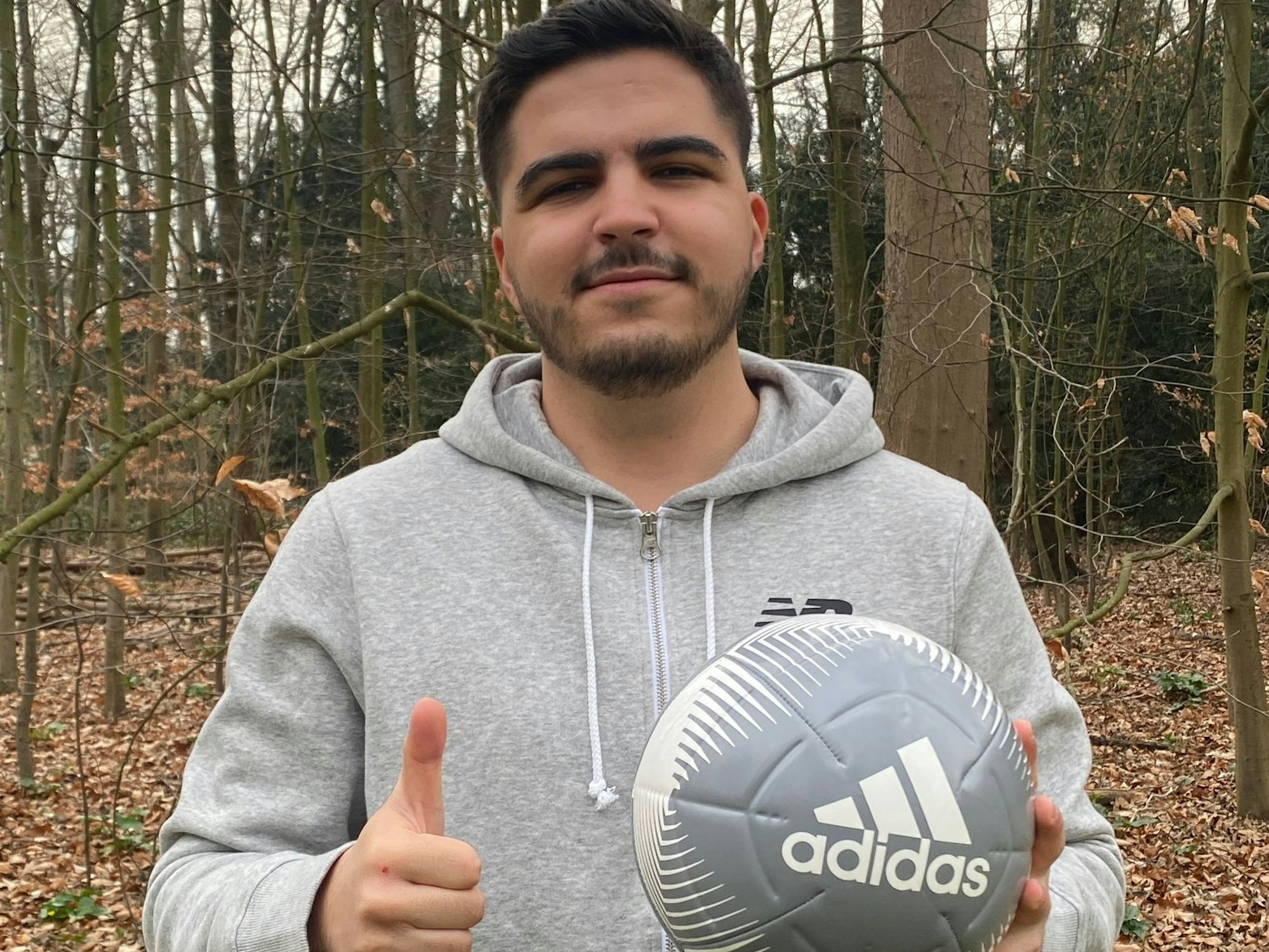 Der Krefelder Amateurfußballer Kürsat Karadag hält den Daumen in die Kamera und lächelt.