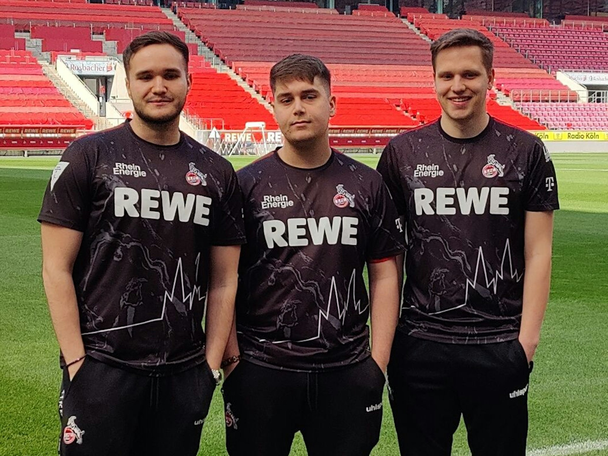 Die E-Sportler des 1. FC Köln stehen auf dem Rasen im Rhein-Energie-Stadion.