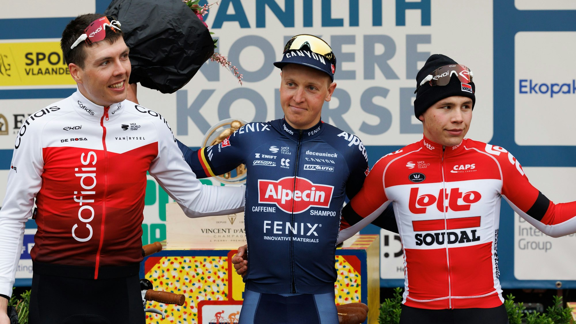 Der Zweitplatzierte Max Walscheid (l-r) aus Deutschland von Cofidis, der Sieger Tim Merlier aus Belgien von Alpecin-Fenix und der Drittplatzierte Arnaud De Lie aus Belgien von Lotto Soudal, feiern auf dem Podium.