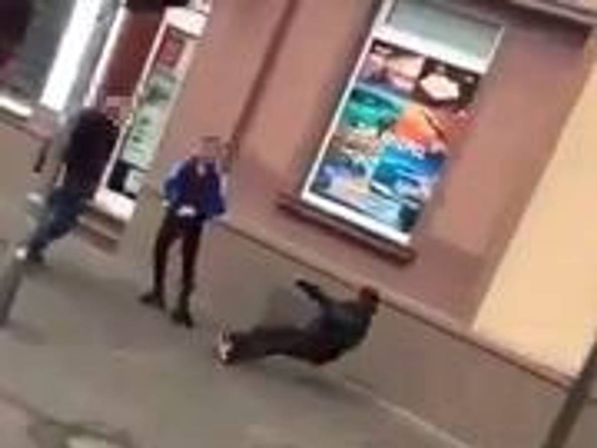 Ein Mann fällt rückwärts zu Boden, zwei Jugendliche stehen vor ihm.
