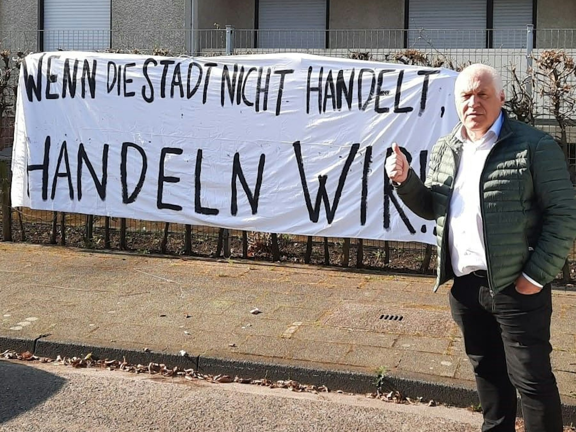 Kalle Gerigk steht vor dem besetzten Haus in Köln und hält den Daumen hoch.