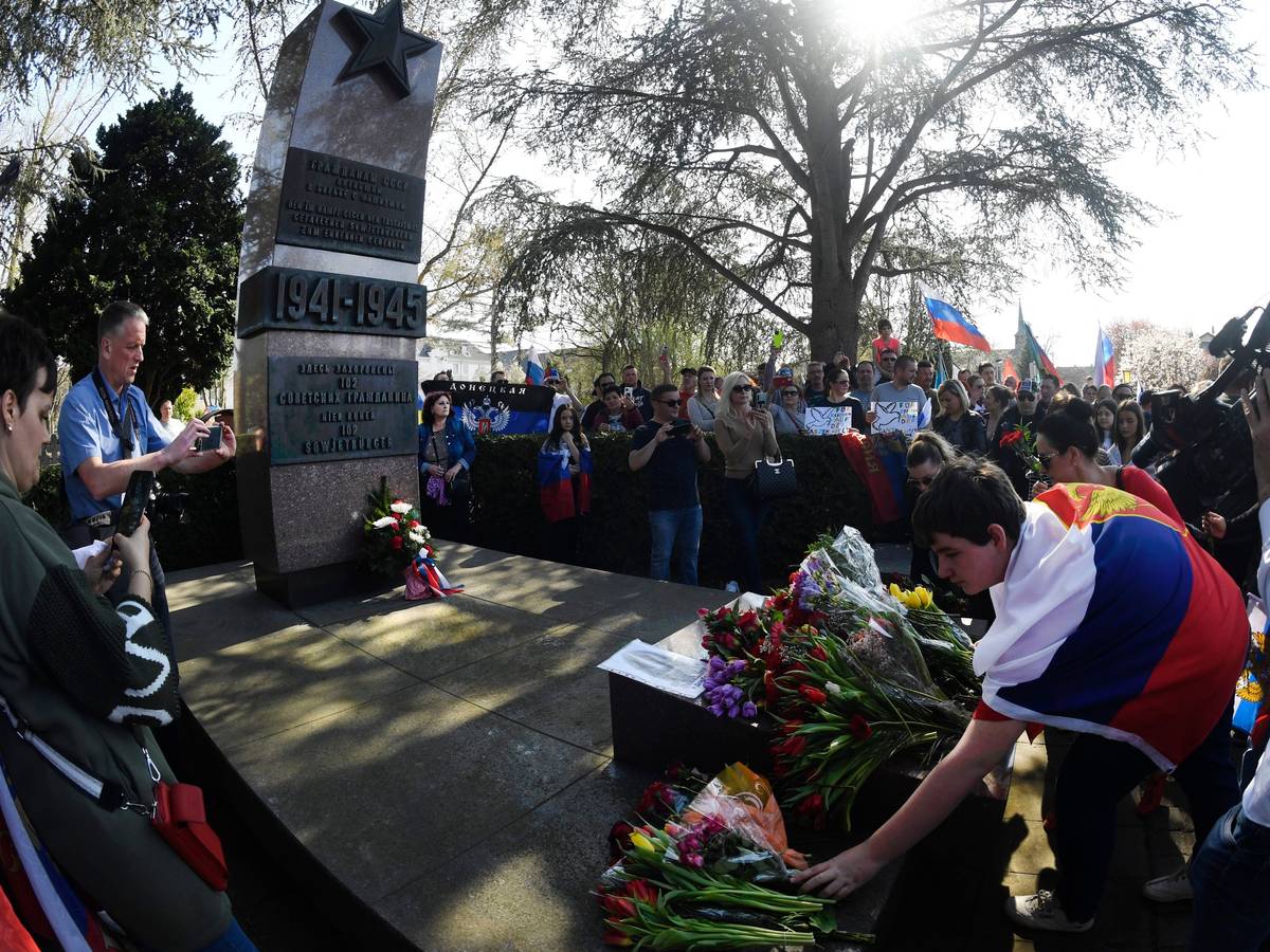 Menschen mit Russland-Fahnen legen Kränze an einem Ehrenmal nieder.