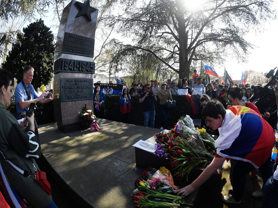 Menschen mit Russland-Fahnen legen Kränze an einem Ehrenmal nieder.