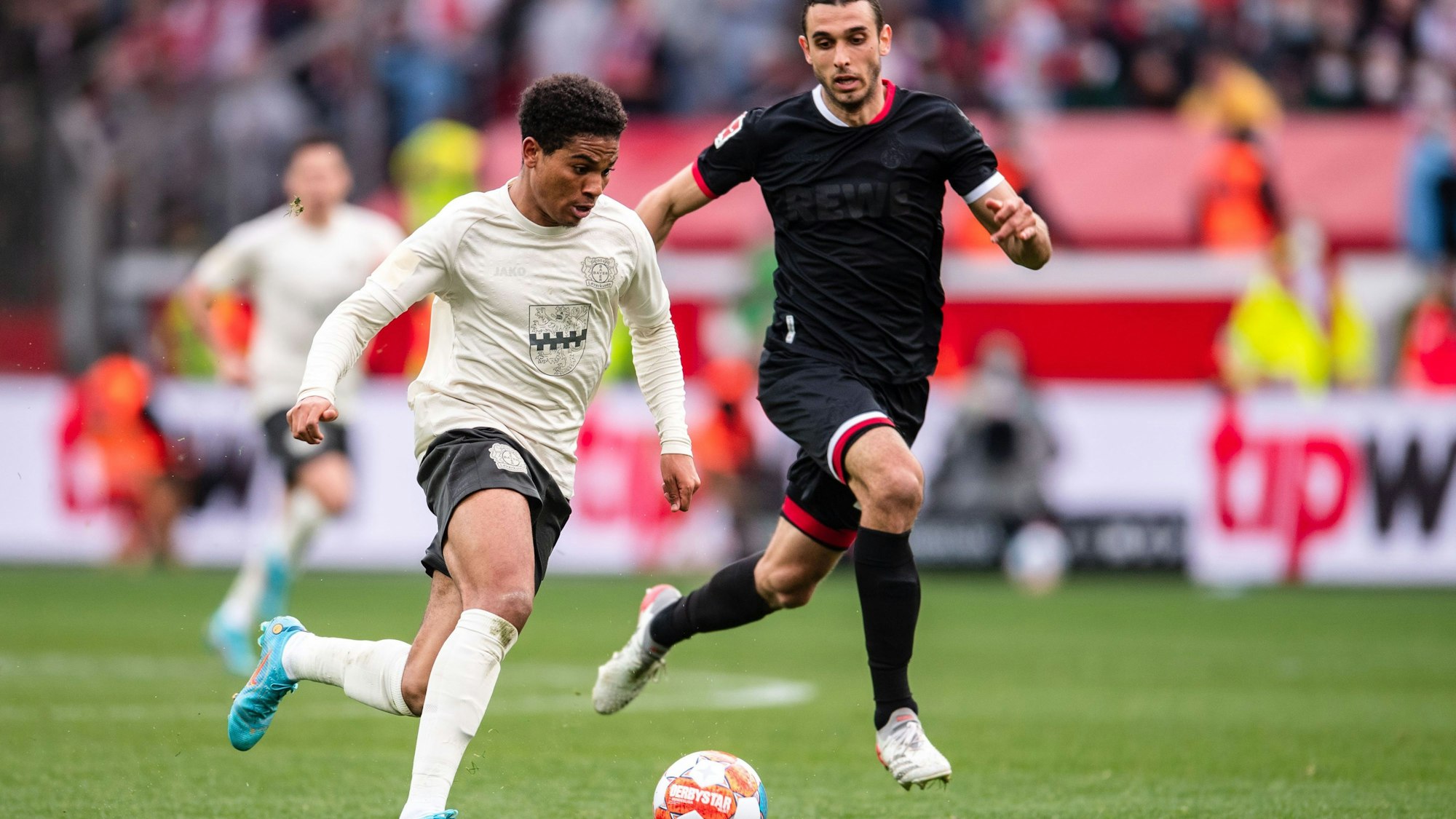 Leverkusens Amine Adli (l) spielt im Laufduell mit Ellyes Skhiri den Ball.