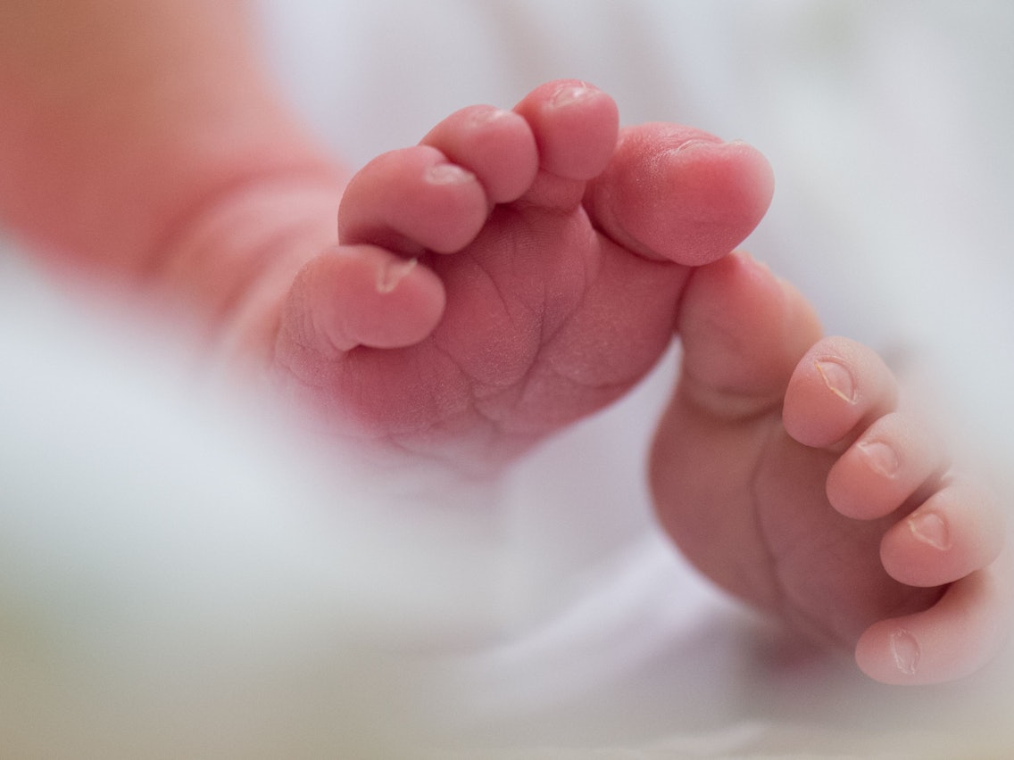Ein Säugling liegt in einem Bett auf der Wochenstation in einem Universitätsklinikum.